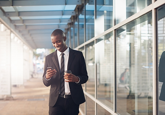 man looking at his phone while standing in an office foyer