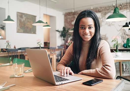 lady sitting at her workspace with her laptop smiling